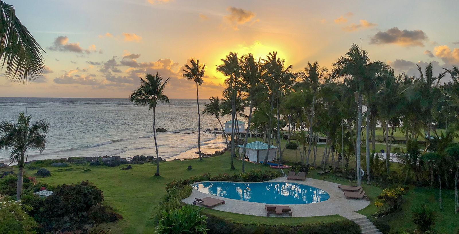 Villa Serena's oceanfront pool and gardens at sunset